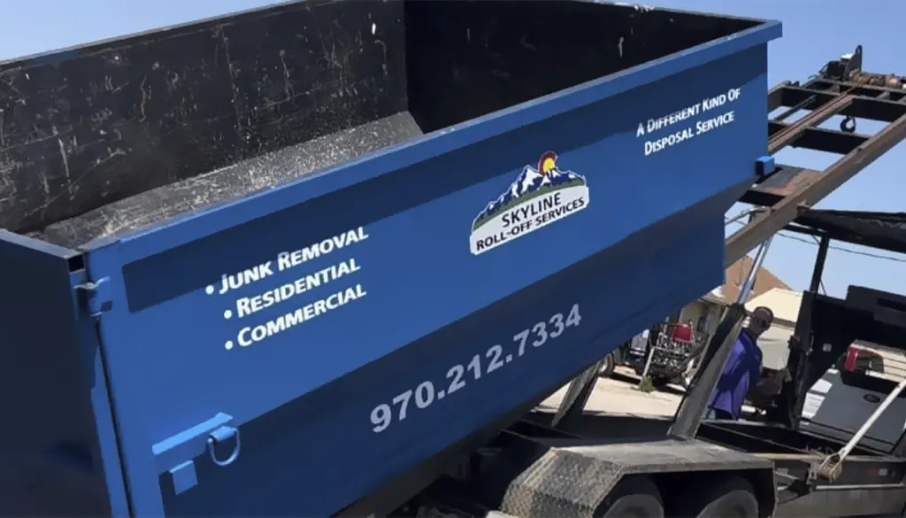 close up of empty dumpster rental being offloaded from delivery truck